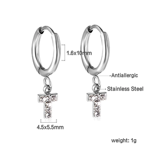 Détail macro de boucles d'oreilles lettre T en acier inoxydable avec zircons blancs brillants