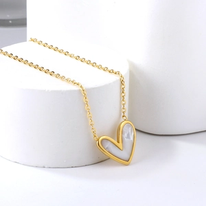 Collier doré minimaliste avec pendentif cœur en nacre sur support blanc