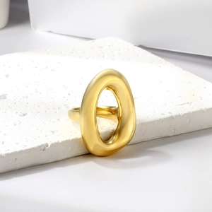 Detailed view of an irregular organic gold ring on a textured white stone pedestal