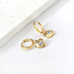 Boucles d'oreilles cœur dorées avec cristaux blancs sur présentoir en marbre