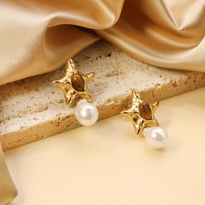 Starfish pearl earrings with brown cat-eye stone on luxury gold silk and marble background