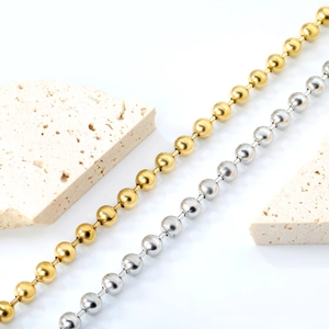 Gold and silver stainless steel bead bracelets displayed on elegant stone props