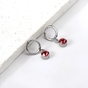 Détail macro de boucles d'oreilles créoles avec pendentifs en pierre rouge facettée