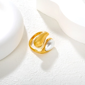Detail view of gold asymmetric water drop ring with white pearl on stone surface