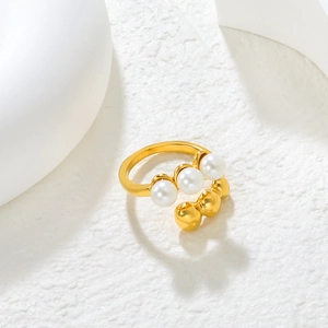 Detail view of 18K gold plated ring featuring white pearls and golden beads on stone surface