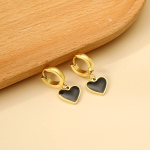 Détail macro des boucles d'oreilles cœur en émail noir avec bords dorés