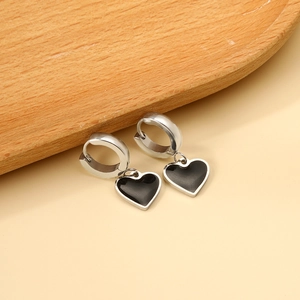 Détail de boucles d'oreilles argentées avec cœurs noirs sur plateau en bois