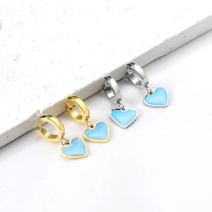 Détail de créoles en or et argent avec des pendentifs en forme de cœur bleu clair