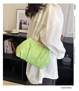 Detail of neon green pleated cloud bag with a sparkling diamond butterfly metal clasp