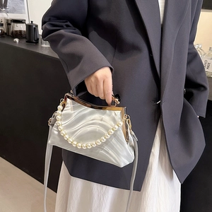 White shell bag with pearl handle and satin ripple texture worn by a model