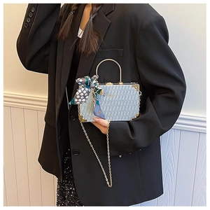 Close-up of silver box bag with wave texture, golden handle, and polka dot scarf