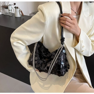 Detail of a chic black sequin handbag with a metallic silver chain and knot strap