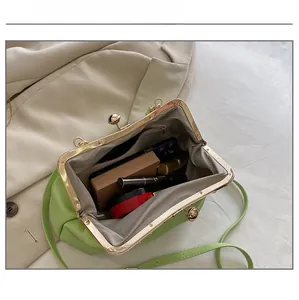 Detail showing the inner storage of a pleated grass green bag with everyday essentials