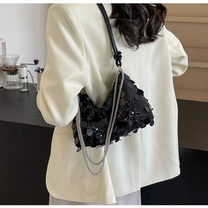 Detail of black sequined crossbody bag with silver chain strap and knot detail