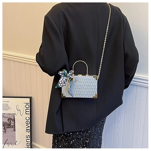 Detail of silver box bag with gold handle and decorative polka dot silk scarf
