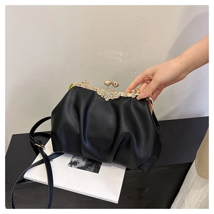 Close-up of black pleated clutch featuring gold metal frame and sparkling floral rhinestone clasp