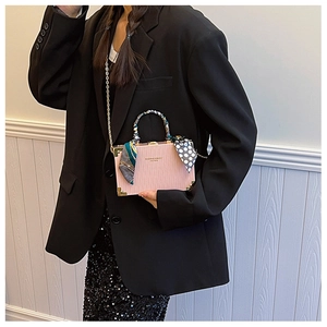 Close-up of pink box bag with wave texture, gold metal corners and silk scarf handle