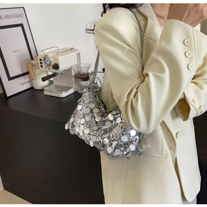 Close-up of silver sequin hobo bag with metal chain strap worn with a cream blazer