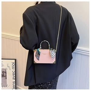 Detail of pink box bag with wave texture, decorative silk scarf and gold chain strap