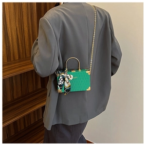 Model wearing a green wave-textured mini box bag with gold chain and silk scarf