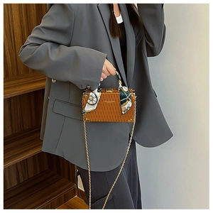 Brown box bag with vertical texture, silk scarf handle, and gold metal corners on model