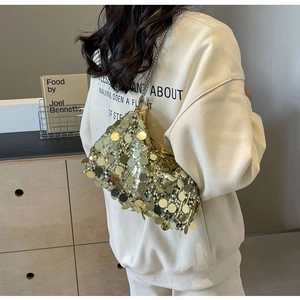 Detail of gold sequin crossbody bag with silver chain strap shown on a model