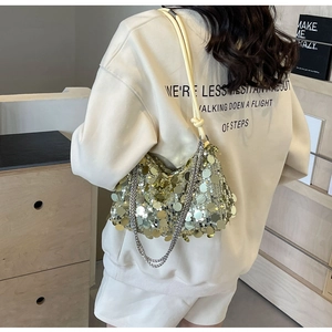 Detail of elegant sequined crossbody bag with metallic chain strap worn by a model