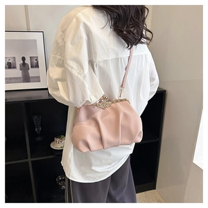 Detail of pink pleated shell bag with metal frame closure and bow accent on a model