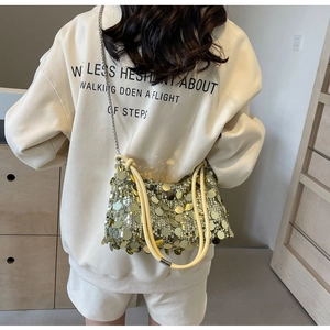 Detail of yellow sequin evening bag with silver chain and beige cylindrical handle
