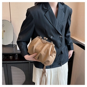 Detail of beige pleated cloud bag with silver rhinestone flower clasp on black suit