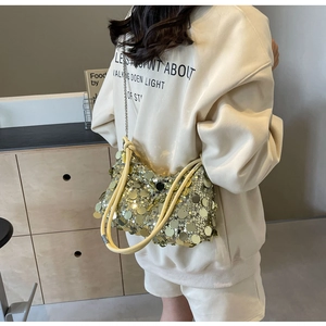 Detailed view of yellow large sequins texture and metallic chain strap on a handbag
