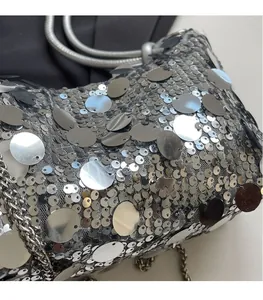 Macro shot of silver sequins on grey mesh fabric with metallic chain strap detail