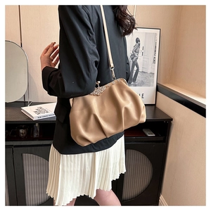Detail of khaki pleated cloud bag featuring a crystal butterfly clasp and gold hardware