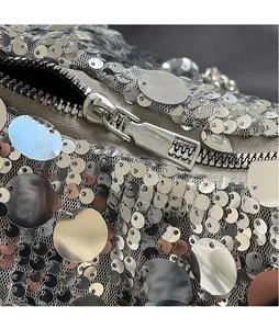 Close-up of smooth silver metal zipper and glittering sequins on a stylish handbag