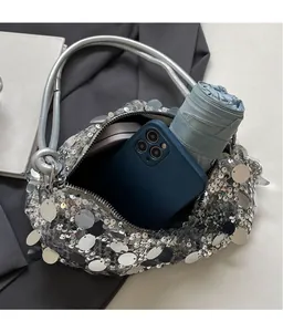 Internal storage view of silver sequin handbag holding a smartphone and a folded umbrella