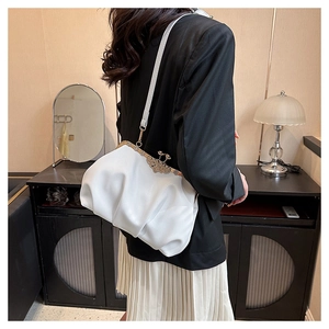 Detail of white pleated cloud bag featuring vintage gold floral clasp and slim shoulder strap