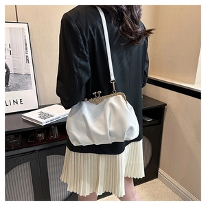 Detail of white pleated shell bag with vintage metal frame clasp on model