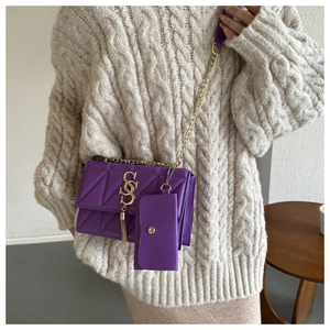 Détail du sac à bandoulière matelassé violet avec boucle S dorée et gland sur pull beige