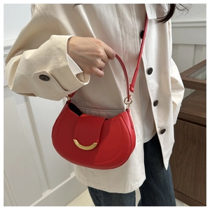 Detail of red crescent moon saddle bag with a minimalist golden ring buckle and slim strap