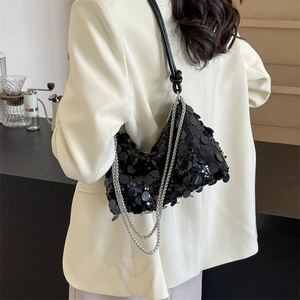 Elegant black sequin handbag with silver chain strap shown in a modern urban setting