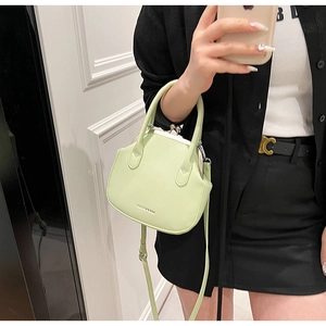 Detail of mint green leather kiss-lock bag with top handle and adjustable strap
