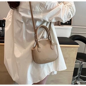Detailed view of khaki leather frame bag with metal clasp and adjustable shoulder strap