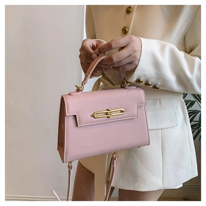 Detalle de bolso rosa con textura de palma y hebilla dorada en modelo elegante