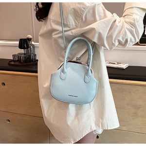 Detail view of light blue leather bag with vintage metal clasp and fashion slogan print