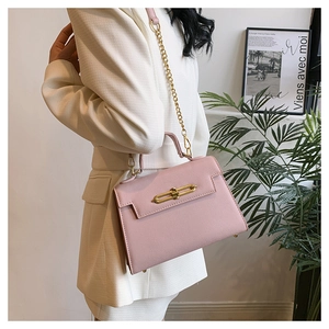 Detalle de bolso bandolera rosa en piel granulada con herrajes dorados y cadena