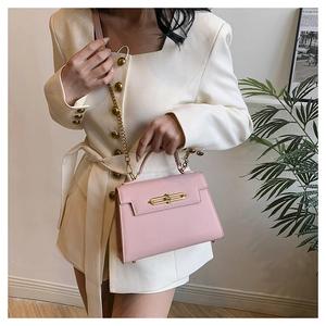 Detalle del bolso rosa con textura de grano cruzado y correa de cadena de metal dorado