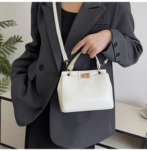 Close-up of off-white retro crossbody bag with gold twist-lock and slim leather strap