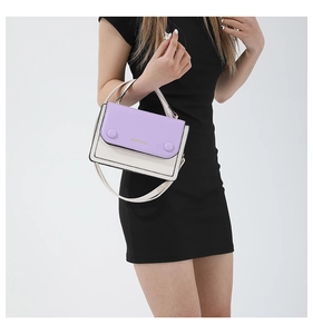 Detail of color-block crossbody bag featuring purple and white panels with gold logo