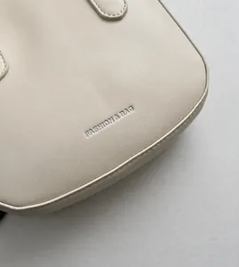 Macro detail of beige leather shell bag with embossed Fashion & Bag lettering and stitching