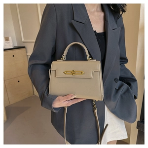 Detalle de mini bolso beige en piel texturizada con cierre dorado y correa de hombro